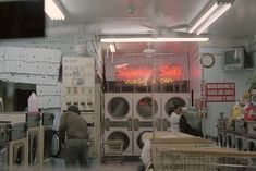 two people are standing in front of washers and dryers at the laundry shop