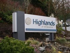 the sign for highlandss is shown in front of some bushes and trees with houses behind it