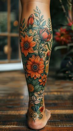 a woman's legs with flowers and leaves tattooed on the bottom of her leg