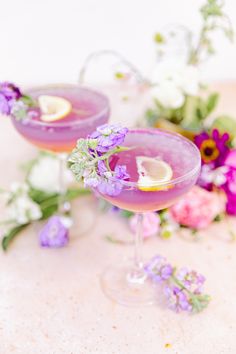 two glasses filled with purple liquid and garnished with flowers