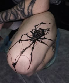 a spider tattoo on the leg of a person with tattoos on their legs and arms