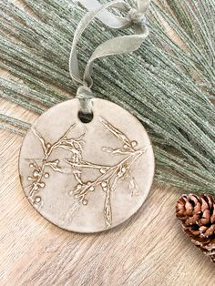 a ceramic ornament with a bird on it next to pine cones and needles