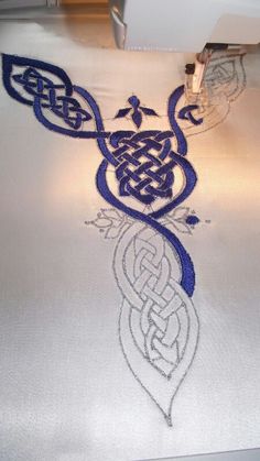 the embroidery is being stitched onto the white fabric with blue thread and an intricate design on it