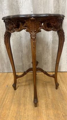 an antique wooden table with carvings on the top and bottom, sitting on a hard wood floor