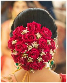 a woman with a bunch of red roses in her hair is wearing a bridal hairstyle