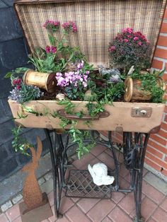 an old sewing machine with plants growing out of it's side table on the sidewalk