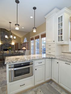 a large kitchen with white cabinets and granite counter tops, along with marble flooring