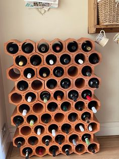 a wine rack made out of clay with bottles in it on the floor next to a wall