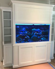 an aquarium is built into the side of a bookcase in a room with white walls