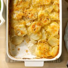 a casserole dish with potatoes and parmesan cheese in it on a wooden table