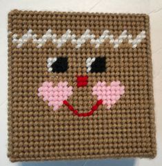 a close up of a knitted square with a face on it