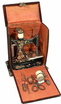 an old sewing machine in its case with scissors and other items inside it on a white background