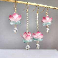 Our lotus flower design was inspired by the Lotus and Water Lily Festival at Kenilworth Park in D. C. Handcrafted with intricate details, these earrings are the perfect accessory for nature lovers and flower enthusiasts. These are handmade with resin flowers, crystal beads, glass leaves and 14K gold plated earring hooks which are good for delicate ears. You could choose the short, long or mix length design. The short version (W x L) : 0.75" x 2" The long version ( W x L) : 0.75" x 3" The mix len Genshin Impact Earrings Clay, Lotus Flower Accessories, Water Lily Earrings, Julary Design, Elegant Resin Flower Earrings, Elegant Resin Flower-shaped Earrings, Elegant Resin Earrings With Flower Charm, Lotus Flower Earrings, Pretty Jewellery Earrings