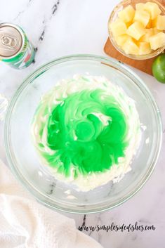 a green and white cake sitting on top of a glass bowl next to a can of soda