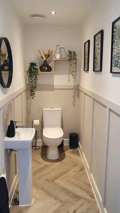 a white toilet sitting in a bathroom next to a sink and mirror on the wall