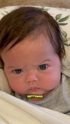 a baby with blue eyes laying in a crib