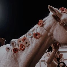 a woman petting a white horse with flowers on it