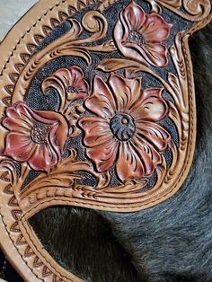 a close up of a horse's leather saddle with flowers on the back and sides