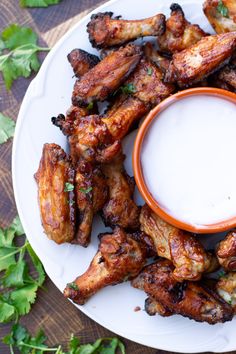 chicken wings on a plate with ranch dressing and cilantro garnishes