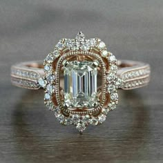 a fancy engagement ring with an emerald center surrounded by white and rose gold pave