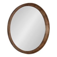 a round wooden mirror hanging on the wall in front of a white background with a reflection