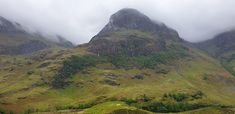 the mountains are covered in clouds and grass