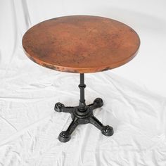 an old wooden table with cast iron legs on a white sheeted surface in front of a white backdrop