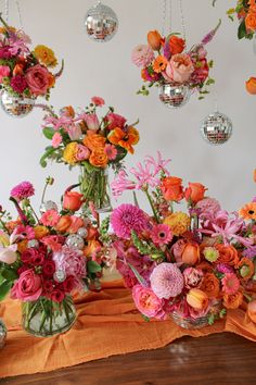 a table topped with vases filled with different types of flowers and disco balls hanging from the ceiling