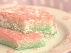 two pieces of powdered sugar sit on a plate with pink and green sprinkles