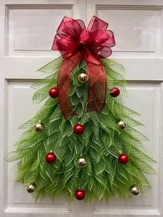 a door decorated with a christmas tree made out of green leaves and red balls is shown