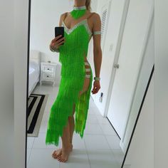 a woman in a green dress is taking a selfie with her cell phone and looking into the mirror