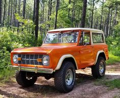 an orange jeep is parked in the woods