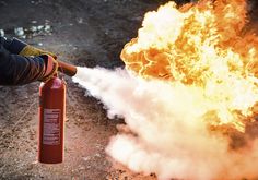 a person holding a fire extinguisher in front of a bunch of flames