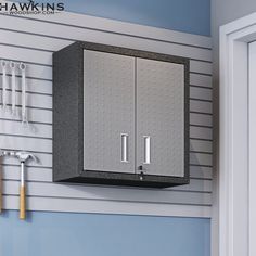 a garage storage cabinet mounted to the side of a wall with tools hanging on it