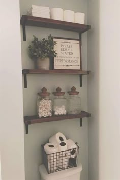 a bathroom with shelves above the toilet and two baskets on the wall next to it