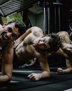 two men are doing push ups in the gym