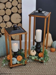 two wooden lanterns sitting next to each other on top of a floor covered in leaves and pumpkins