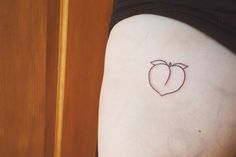 an apple tattoo on the back of a woman's thigh