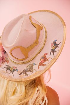 Unleash some playful style with the HORSESHOE PINK RANCHER HAT! This one-of-a-kind hat features a pink color palette with bold gold accents and a cream ribbon band. A racing horses design, gold horse bit patch, and pink floral design add a unique touch, perfect for an unforgettable Derby look. Giddy up! This hat is ONE Pink Curved Brim Felt Hat For Kentucky Derby, Pink Felt Hat With Curved Brim For Kentucky Derby, Pink Fedora Felt Hat For Kentucky Derby, Pink Fedora For Kentucky Derby, Pink Western Hat For Kentucky Derby, Pink Fedora For Party, Pink Wide Brim Mini Hats For Rodeo, Pink Fedora For Kentucky Derby And Rodeo, Pink Felt Hat With Curved Brim For Party