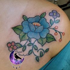 a blue flower tattoo on the back of a woman's shoulder