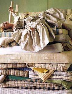 a woman laying on top of a pile of pillows