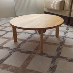 a wooden table sitting on top of a carpeted floor next to a chair and couch