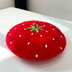 a red pillow with white dots and a green leaf on the top is sitting on a table