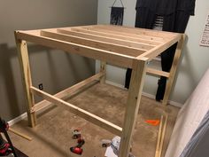 a wooden table sitting in the middle of a room with tools on the floor next to it