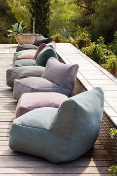 a row of couches sitting on top of a wooden floor next to plants and trees