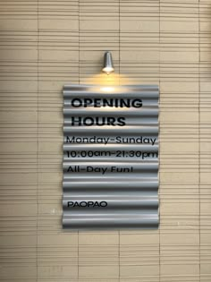 an open hours sign hanging from the side of a wall next to a light fixture