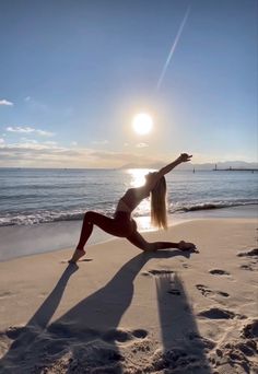 a woman is doing yoga on the beach at sun set in front of the ocean