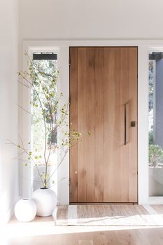 a large wooden door sitting inside of a living room next to a vase filled with flowers