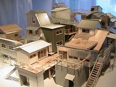 several model houses on display in front of a blue wall with windows and stairs leading up to the second floor