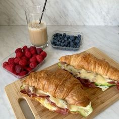 two croissants on a cutting board with berries and milk in the background